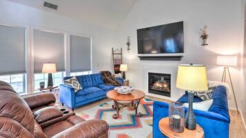 Un salon avec un canapé bleu, un divan en cuir marron, une cheminée et un téléviseur à écran plat.
