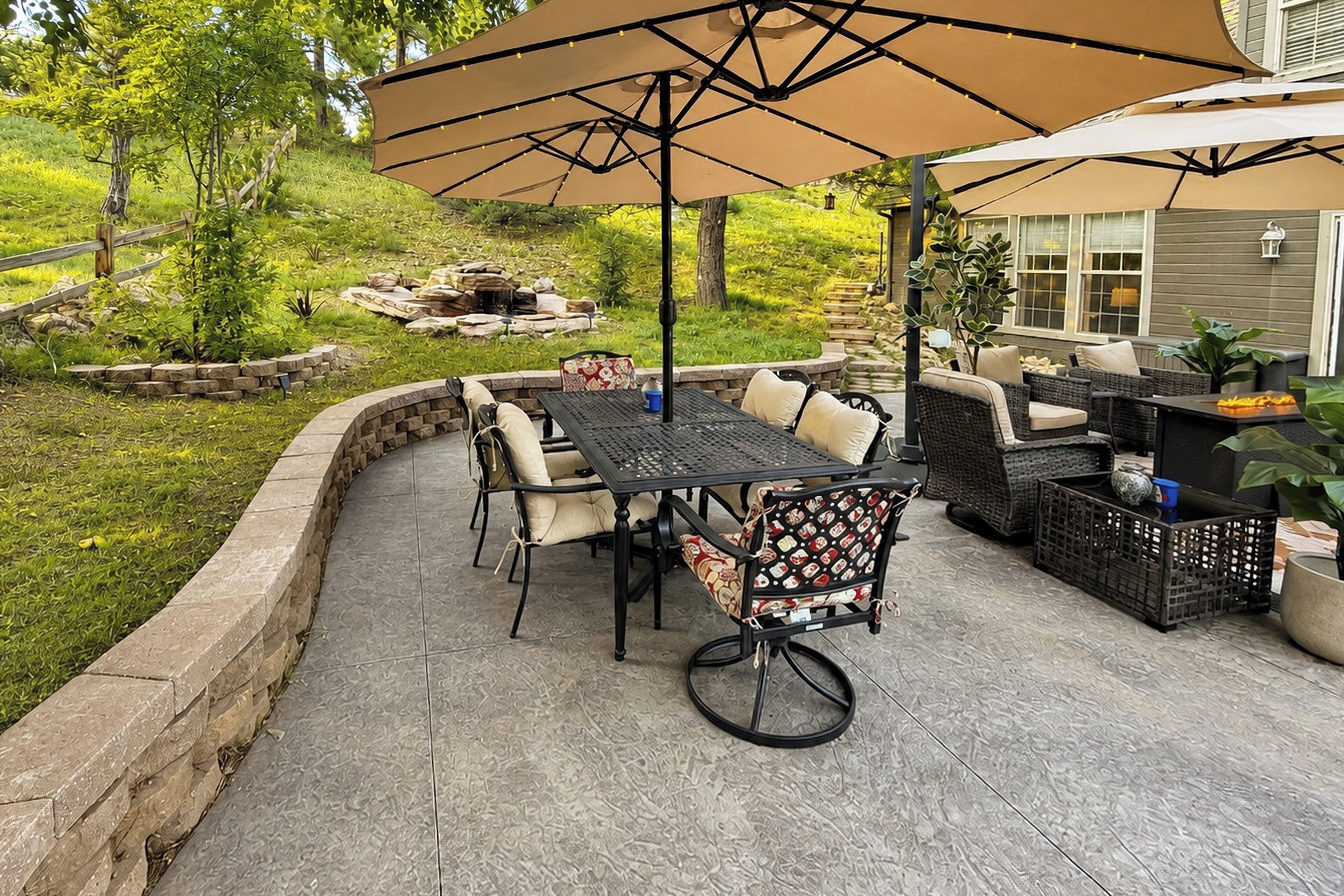 An outdoor patio with a table and chairs, surrounded by a stone wall and a grassy area.