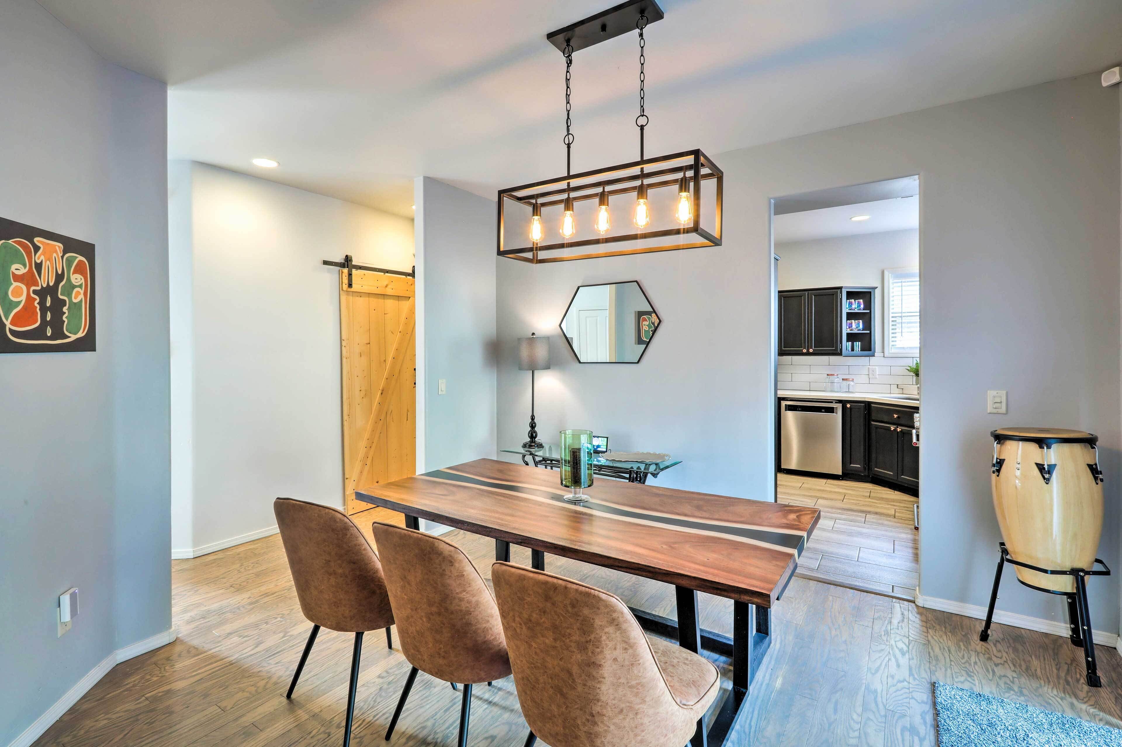 Comedor con mesa de madera, cuatro sillas y una lámpara colgante.