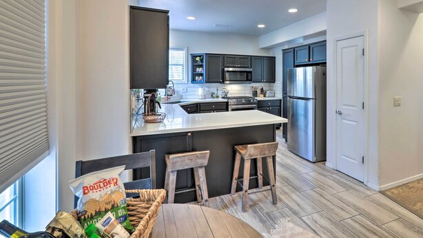 A modern kitchen with dark cabinets, stainless steel appliances, and a central island with stools.