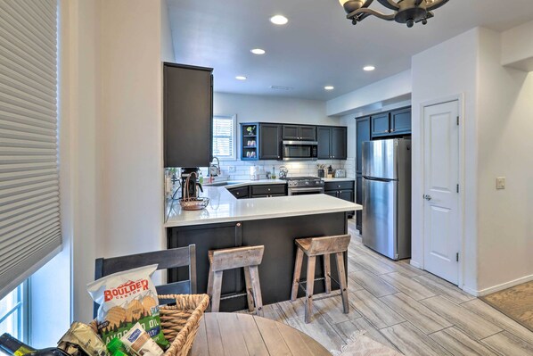 A modern kitchen with dark cabinets, stainless steel appliances, and a central island with stools.