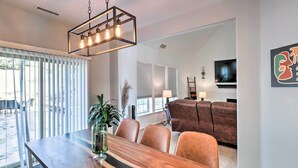 A dining area with a wooden table, chairs, and a hanging light fixture.
