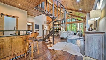 Amplia sala de estar con escalera de madera, un ventanal grande y una decoración rústica.