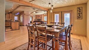 A spacious dining area with a wooden table and chairs, a fireplace, and a view of the kitchen.