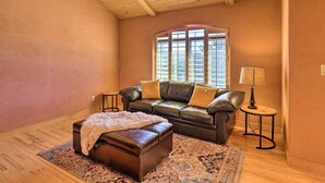 A cozy living room with a leather sofa, a matching ottoman, a patterned rug, and a lamp on a side table.