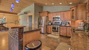 A modern kitchen with wooden cabinets, stainless steel appliances, and a unique island with a mosaic backsplash.