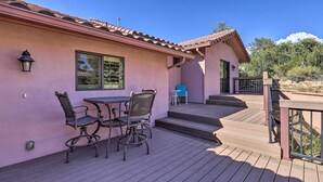 A patio with a table and chairs, a small blue table, and a gate leading to a covered area.
