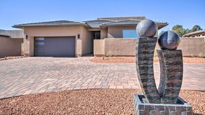Une maison moderne avec une allée pavée, deux sculptures sphériques et un garage.