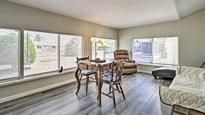 Une pièce spacieuse comprenant une table à manger, des chaises, un canapé et une grande fenêtre donnant sur l’extérieur.