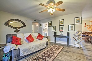 A living room with a sofa, a coffee table, a ceiling fan, a rug, and a bookshelf. - 6 Mi to State Farm Stadium: Wfh-friendly Home! (Sun City)