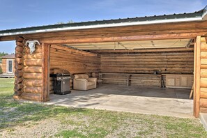 A log cabin with a covered patio, a sofa, and a grill.
