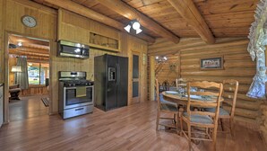 Ein Holzblockhaus-Innenraum mit Küche, Essbereich und einer Uhr an der Wand.
