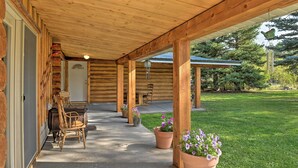 Eine überdachte Veranda mit Holzbalken, einem Betonboden und Topfpflanzen.