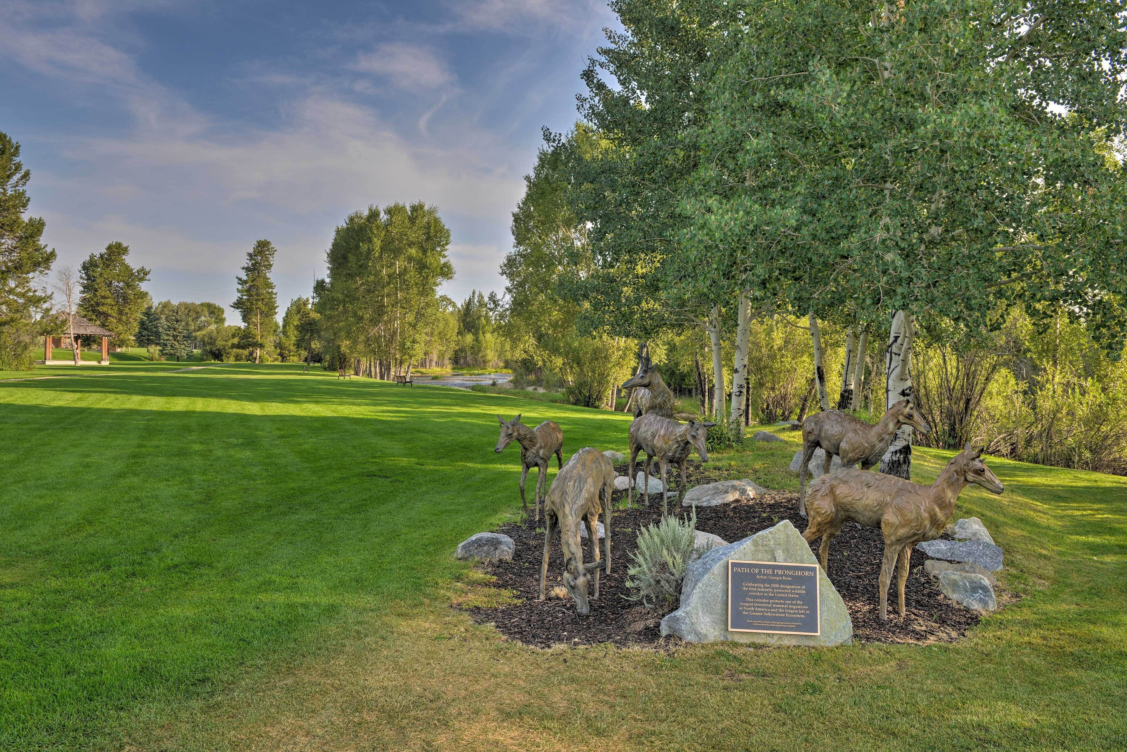 A well-maintained golf course with a sculpture of deer and a plaque.