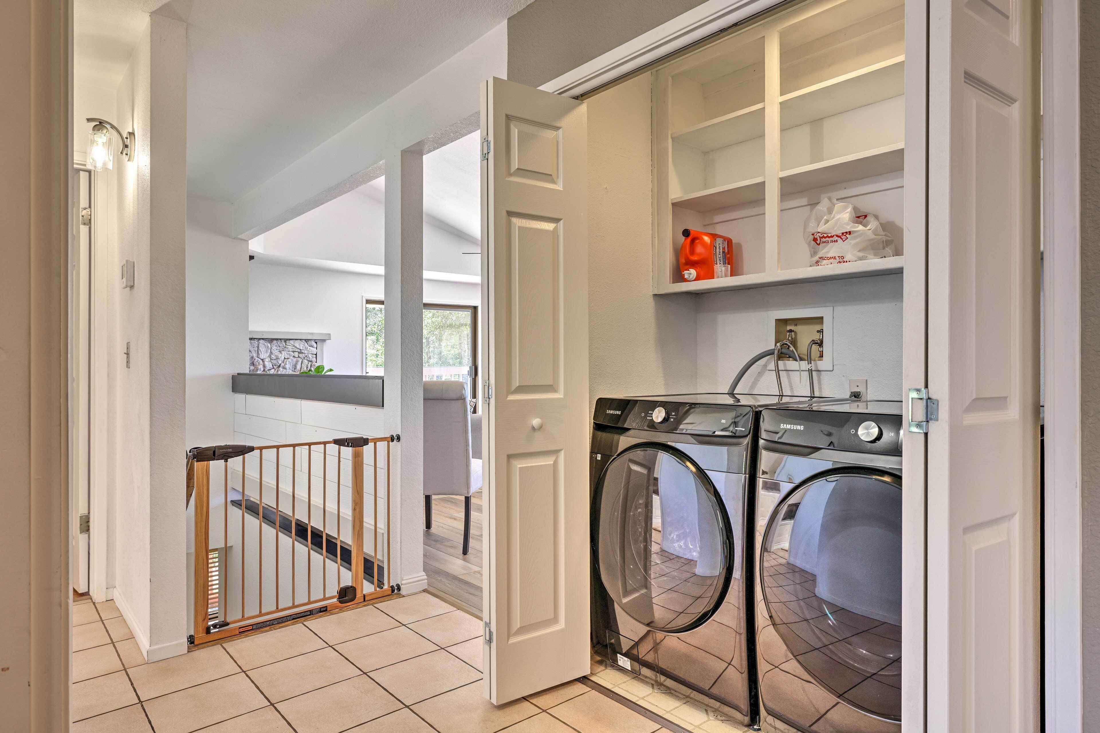 A laundry room with a washing machine, a drying rack, and a storage cabinet.