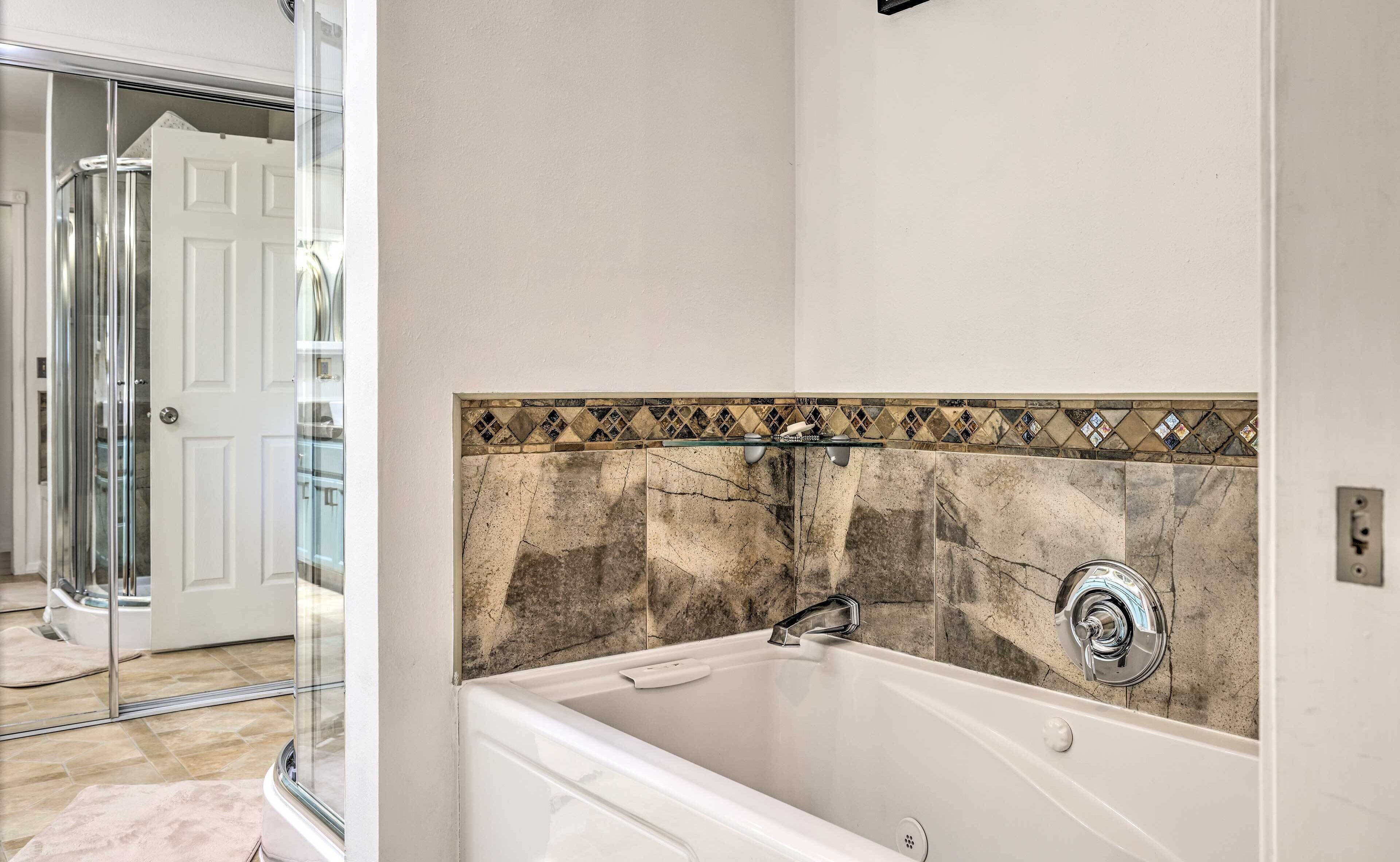 A bathroom with a bathtub, a glass shower enclosure, and a tiled backsplash.