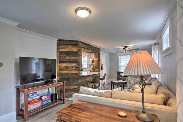 A living room with a TV, wooden console table, sofa, and a lamp. - Pet-friendly Home - 1/2 Mi to Downtown Willoughby! (Willoughby)