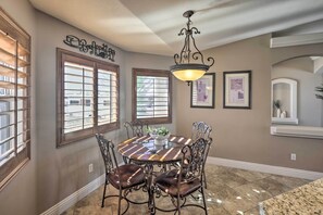 A dining area with a round table, chairs, and a chandelier. - Lake Havasu City House w/ Fire Pit, Pool & Spa! (Lake Havasu City)
