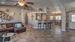 A spacious living area with a brown sectional sofa, a dining table with bar stools, and a ceiling fan. - Lake Havasu City House w/ Fire Pit, Pool & Spa! (Lake Havasu City)