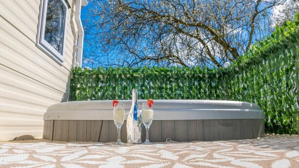 A hot tub with two glasses of champagne in front of a house with a window and a tree in the background. - Tattershall Lakes Private Hot Tub Lodge - Sleeps 6 (Lincoln)