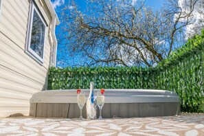A hot tub with two glasses of champagne in front of a house with a window and a tree in the background. - Tattershall Lakes Private Hot Tub Lodge - Sleeps 6 (Lincoln)