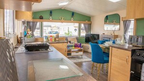 A compact living space with a kitchenette, a dining area, and a seating area with a television. - Tattershall Lakes Private Hot Tub Lodge - Sleeps 6 (Lincoln)