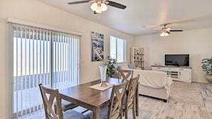 A dining area with a wooden table and chairs, a ceiling fan, and a large window with blinds. - Modern Kingman Vacation Rental, 5 Mi to Dtwn! (Kingman)