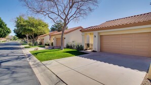 A row of single-story houses with uniform architecture, each featuring a garage door and a well-maintained lawn.