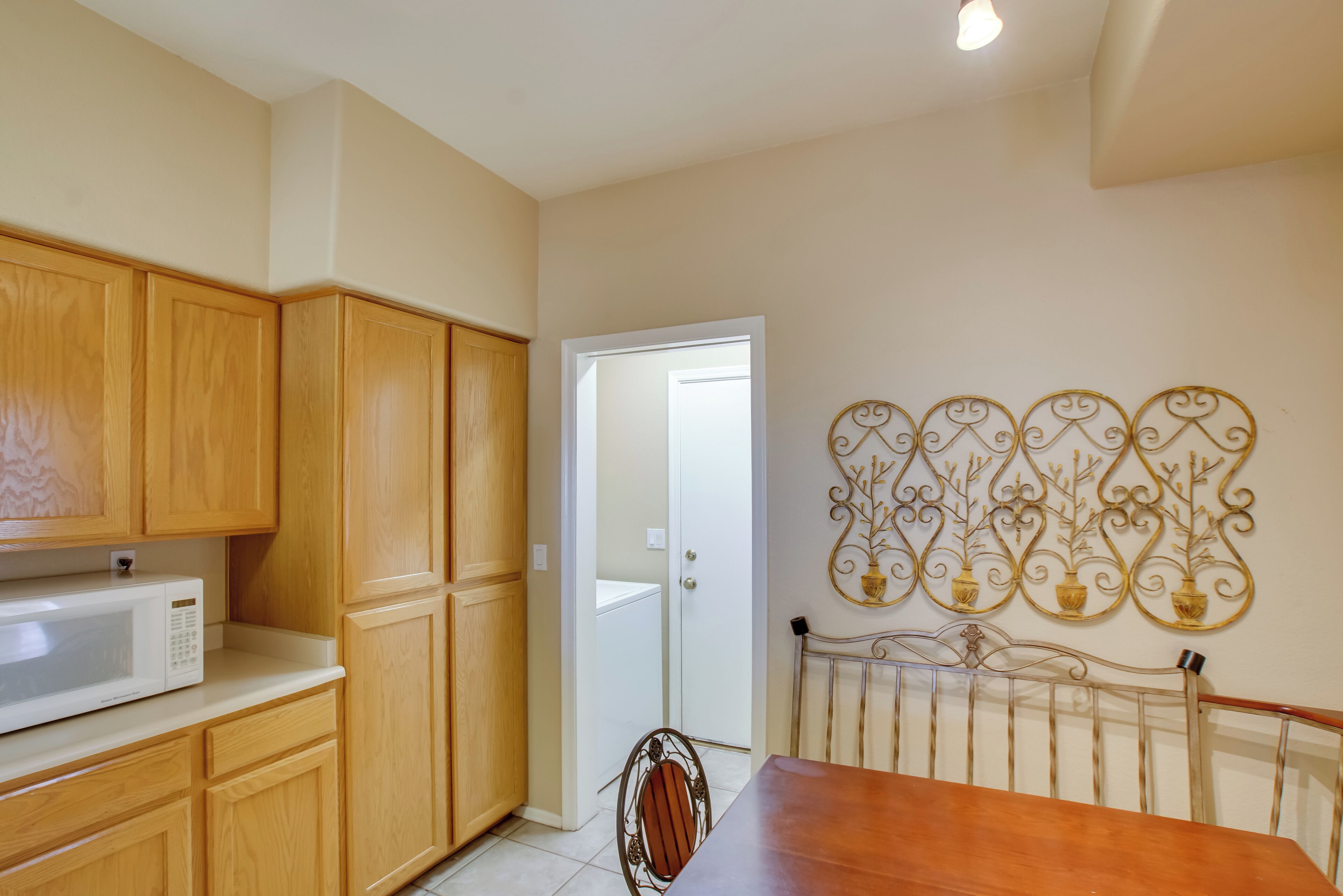 A kitchen with wooden cabinets, a microwave, and a dining table with a metal chair.
