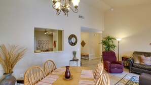 A dining area with a wooden table, chairs, a vase, and a chandelier.