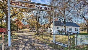 A rustic wooden gate with a sign reading "MAJESTIC ACRES" leading to a house with a white exterior and a dark roof. - Deck, Grill & Yard: Pet-friendly Van Alstyne Gem! (Van Alstyne)