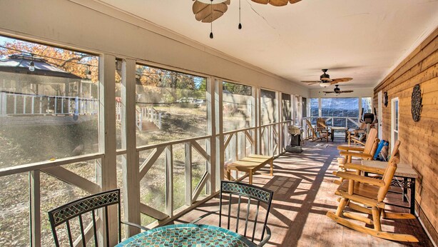 A covered patio with wooden rocking chairs, a table with a mosaic tablecloth, and ceiling fans. - Deck, Grill & Yard: Pet-friendly Van Alstyne Gem! (Van Alstyne)