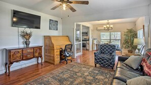 A spacious living room with hardwood flooring, a large wooden cabinet, a black leather sofa, and a patterned rug. - Deck, Grill & Yard: Pet-friendly Van Alstyne Gem! (Van Alstyne)
