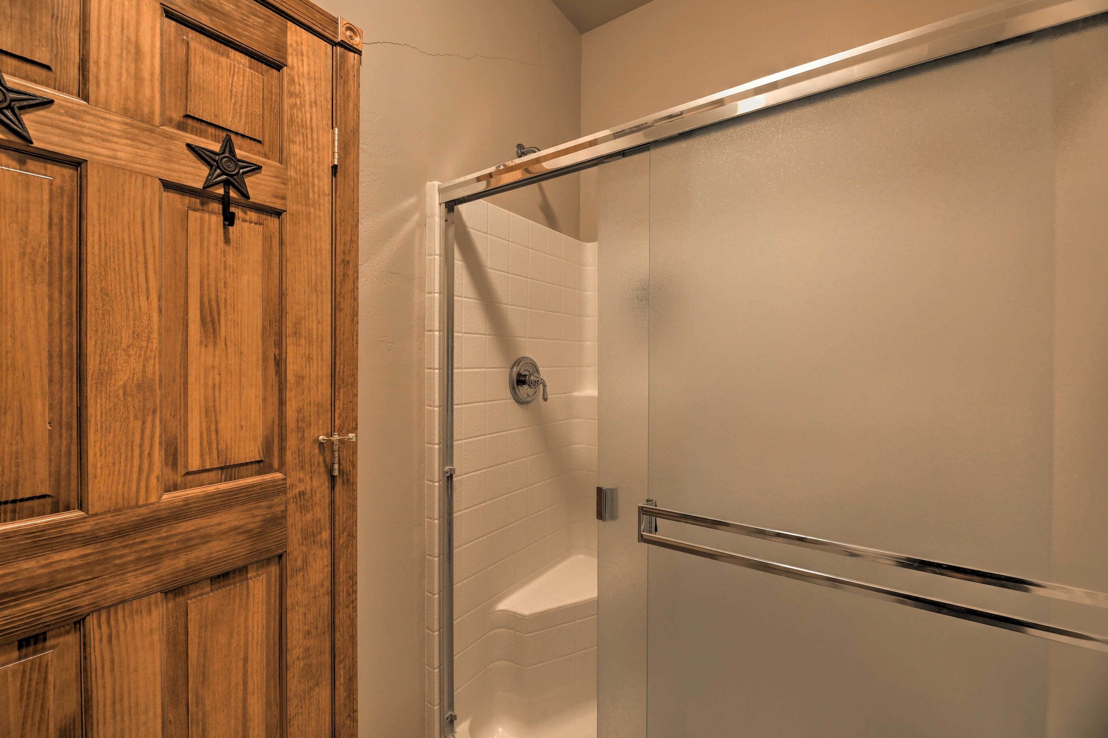 A wooden door with a star-shaped handle and a glass shower door with a metal handle.