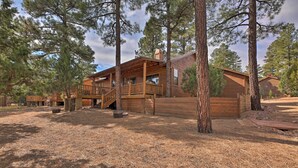 Un bâtiment de style cabane, avec une façade en bois, plusieurs terrasses et une véranda couverte.