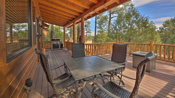 Une terrasse en bois avec une table et des chaises, un barbecue et une vue sur les arbres.