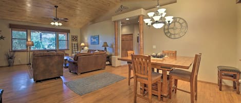 Amplia sala de estar con techo de madera, zona de comedor con mobiliario de madera y ventanas grandes que dejan entrar luz natural.