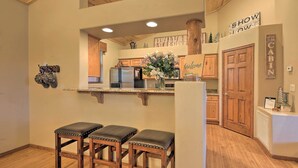 Une cuisine avec des meubles de rangement en bois, un réfrigérateur et un coin bar équipé de tabourets.