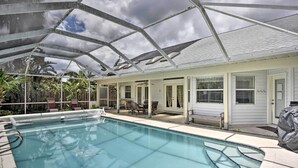 A covered swimming pool area with a glass ceiling, lounge chairs, and a patio with a table and chairs. - Cocoa Beach Paradise: Screened Pool, Patio + Games (Merritt Island)