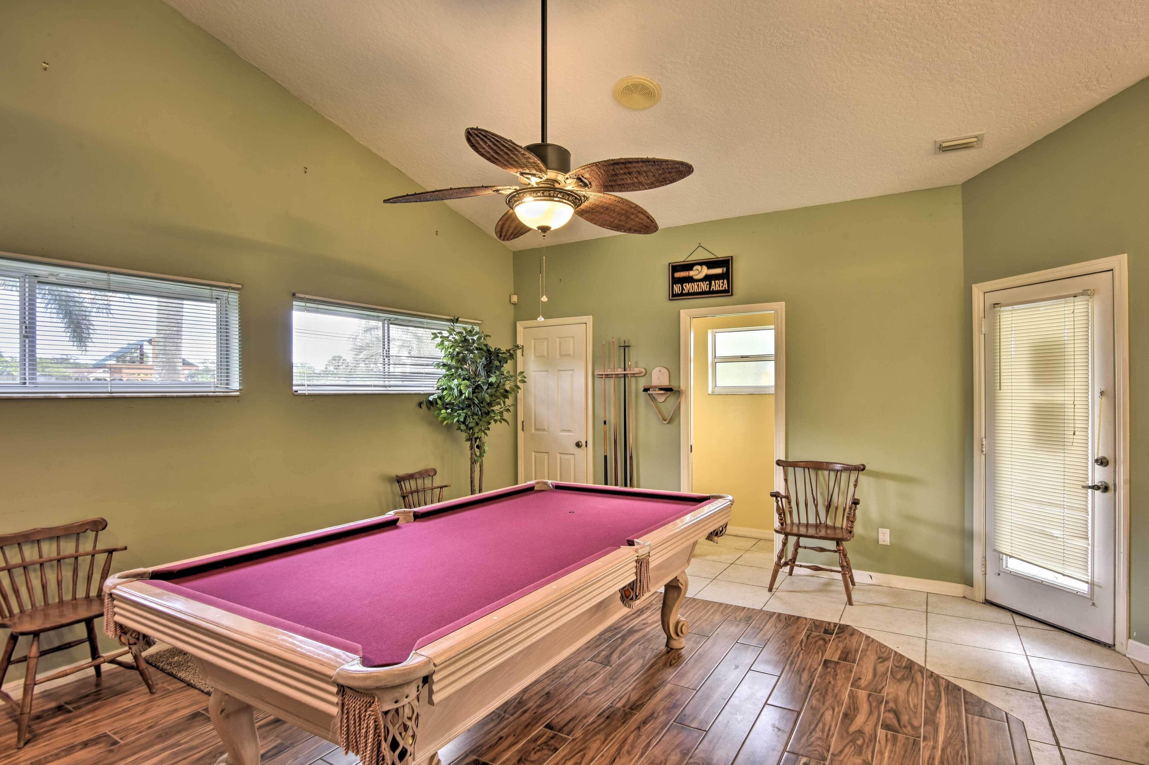 A pool table in a room with green walls, a ceiling fan, and a 'No Smoking Area' sign.