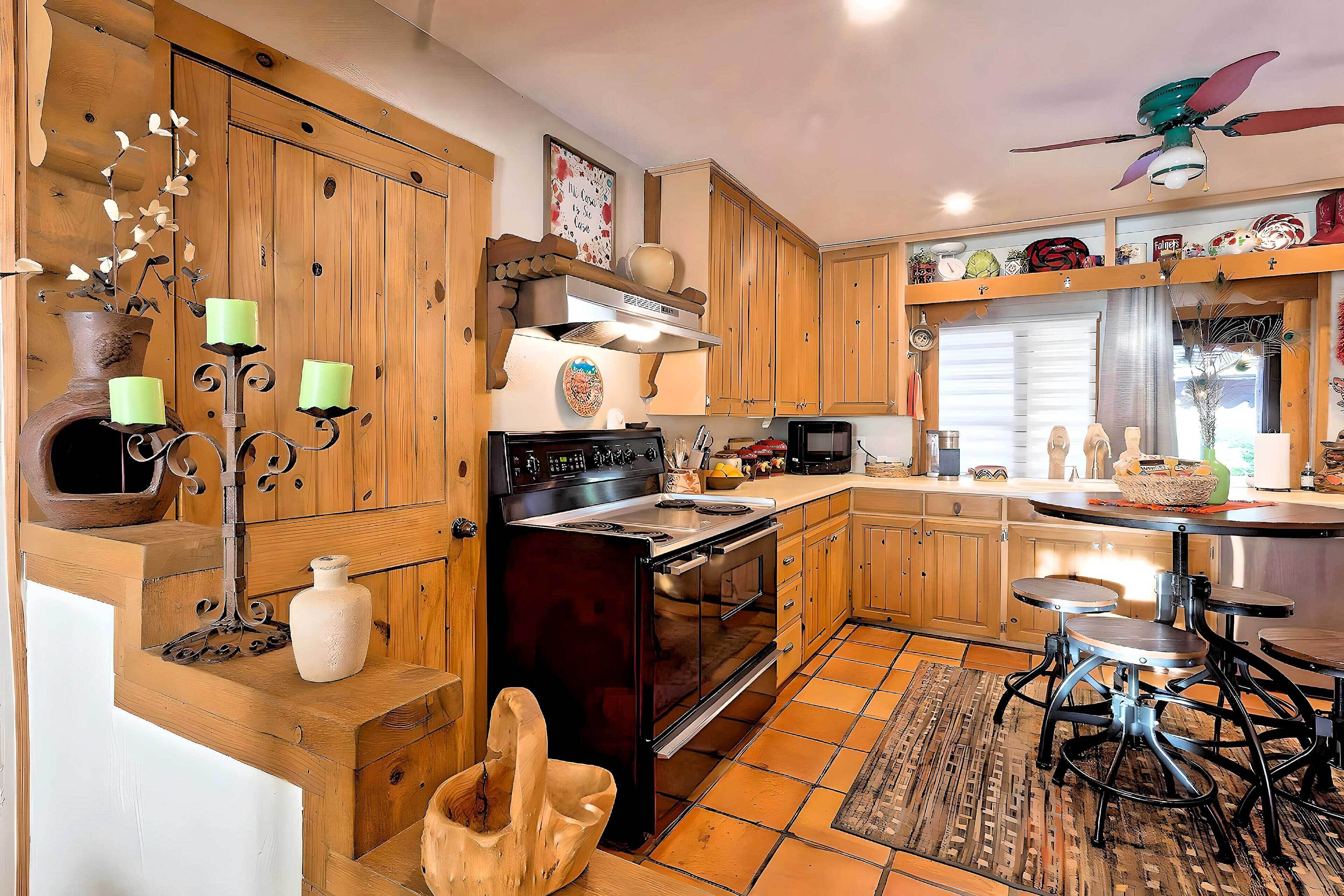 A kitchen with wooden cabinets, a stove, and a dining area with stools.