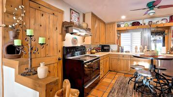A kitchen with wooden cabinets, a stove, and a dining area with stools.