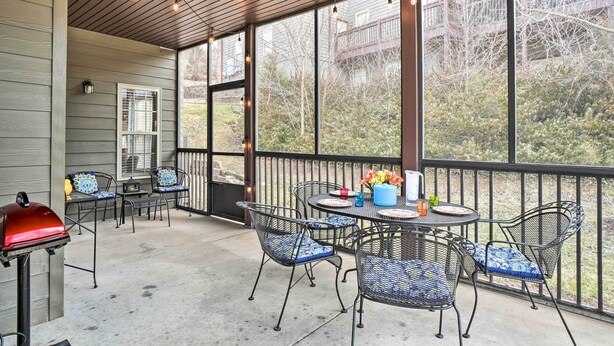 An outdoor patio with metal chairs and a table, a grill, and a view of trees and buildings. - Branson West Villa w/ Golf Course View & Pool! (Branson West)