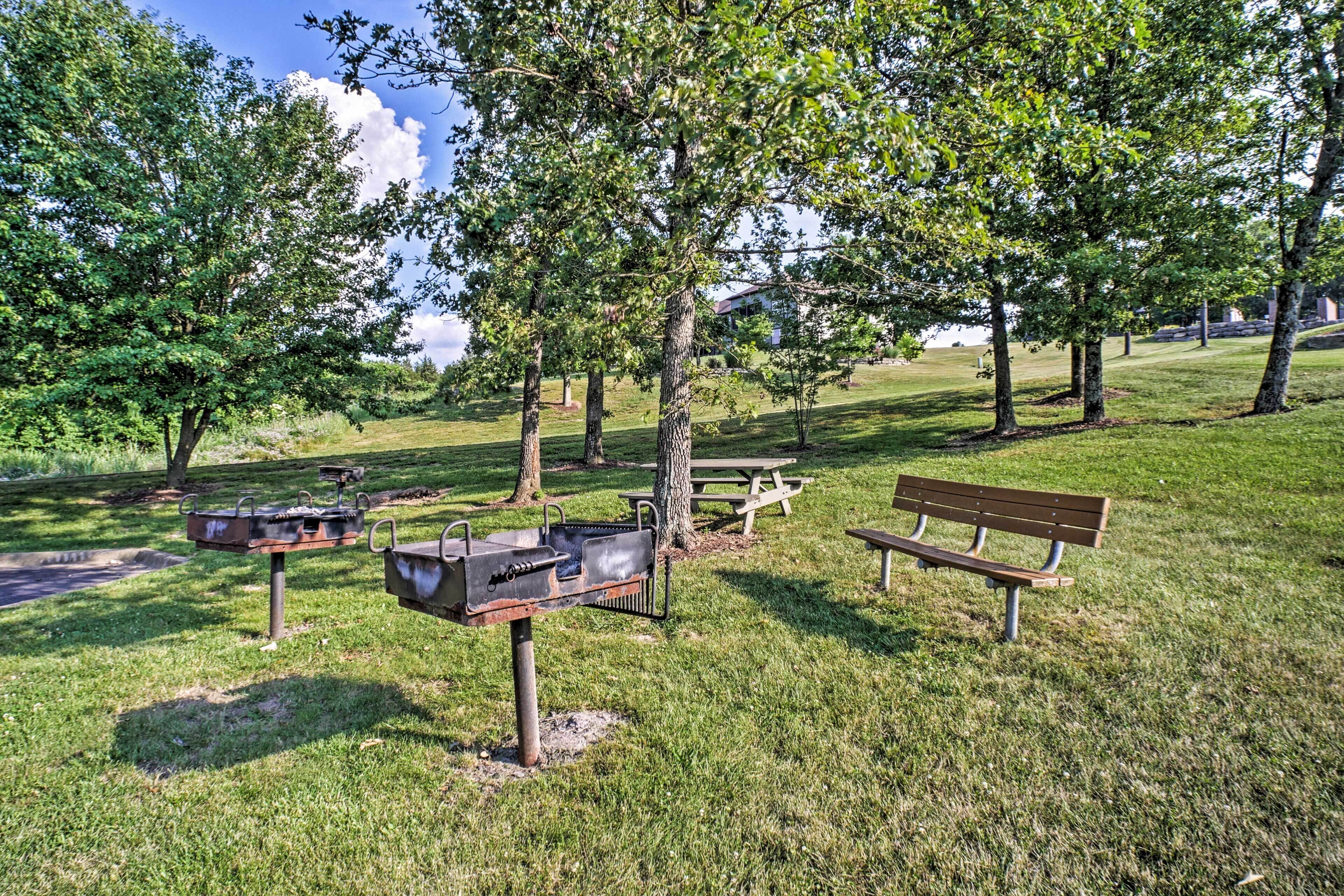 Een park met een barbecue, picknicktafel en bankjes.