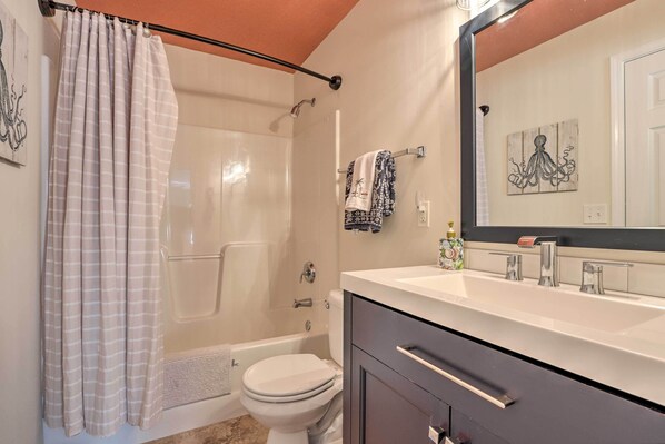 A bathroom with a shower, toilet, and vanity with a mirror.