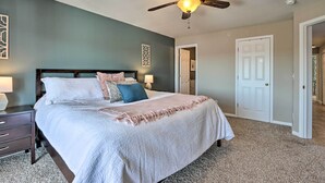 A bedroom with a bed, nightstands, a ceiling fan, and a door. - Relax Poolside! 'serenity at the Lake' in Ozarks (Camdenton)