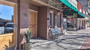 A brick building with a green awning, a fire exit door, and a bench outside. - Bright San Marcos Apartment w/ Ideal Location (San Marcos)