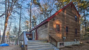 Een houten chalet met een rood dak, een veranda en een trap naar de ingang.