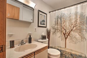 A bathroom with a sink, toilet, and a shower curtain with a tree design. - Lakeview Forest Cabin w/ Deck < 1/2 Mile to Beach! (Madison)