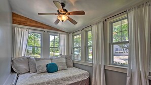 A bedroom with a bed, a ceiling fan, and multiple windows. - Common Fence Point Cottage w/ Ocean Views! (Portsmouth)